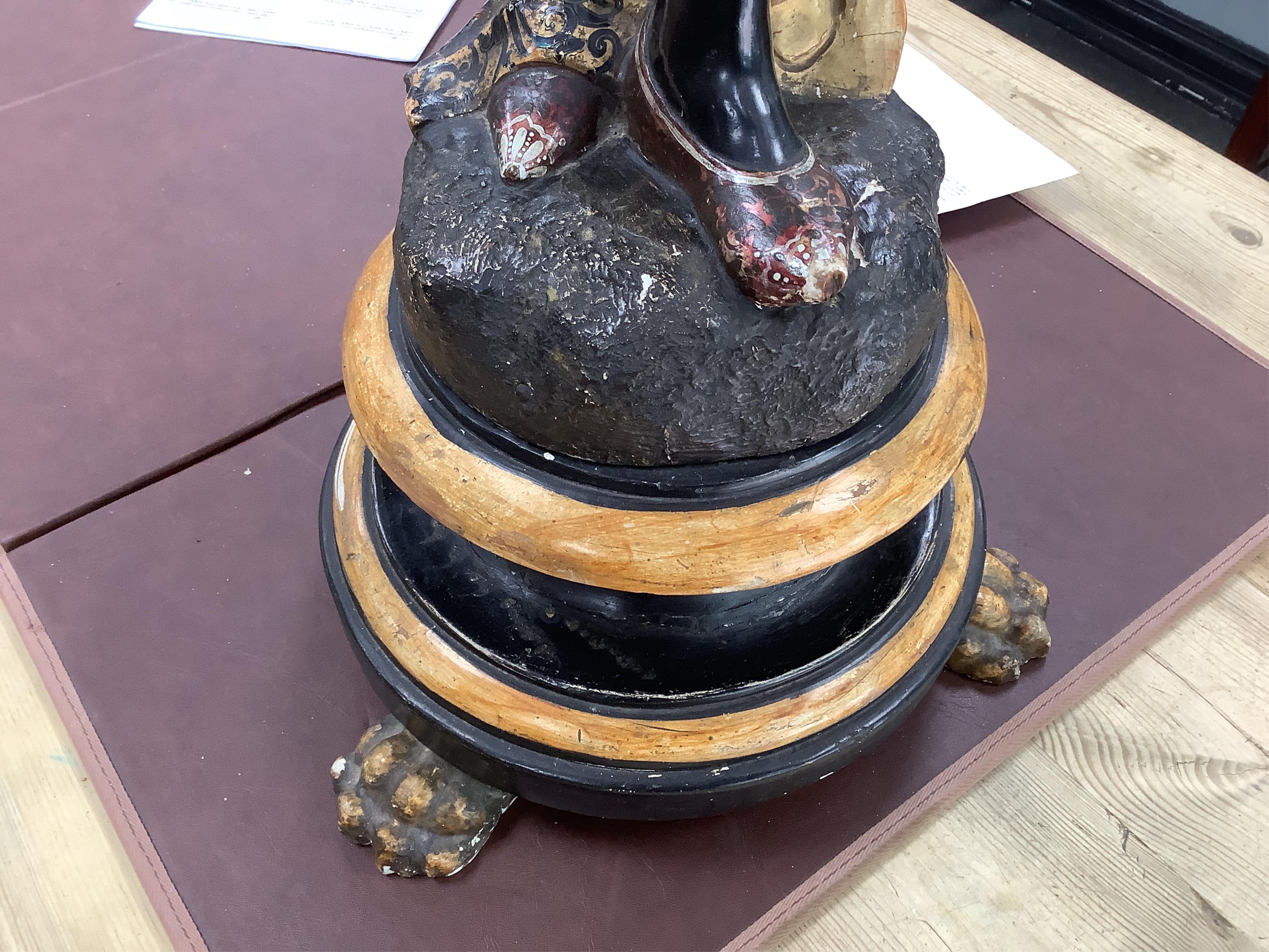 A 19th century Italian carved wood and composition polychrome painted blackamoor torchere, modelled standing with one arm holding a scroll pillar on waisted circular base and lions paw feet, 106cm high